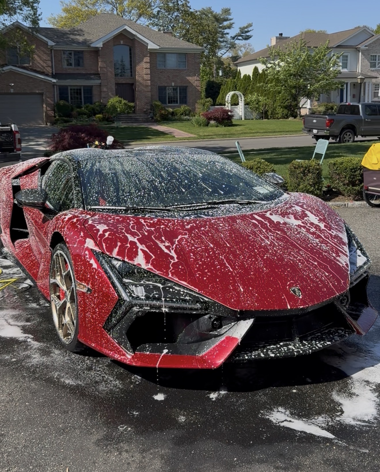 Red sports car covered in foam during a mobile wash